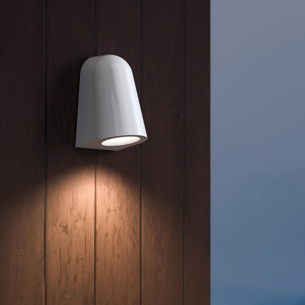White outdoor wall light illuminates a dark wood panelled wall