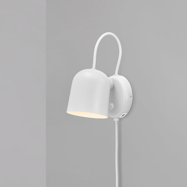A white wall light with a curved arm and bell-shaped shade, emitting a warm glow.