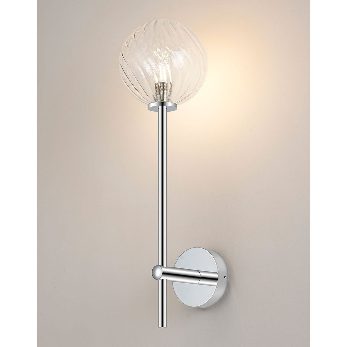 A contemporary wall light with a chrome finish and a clear, swirled glass globe shade, illuminated.