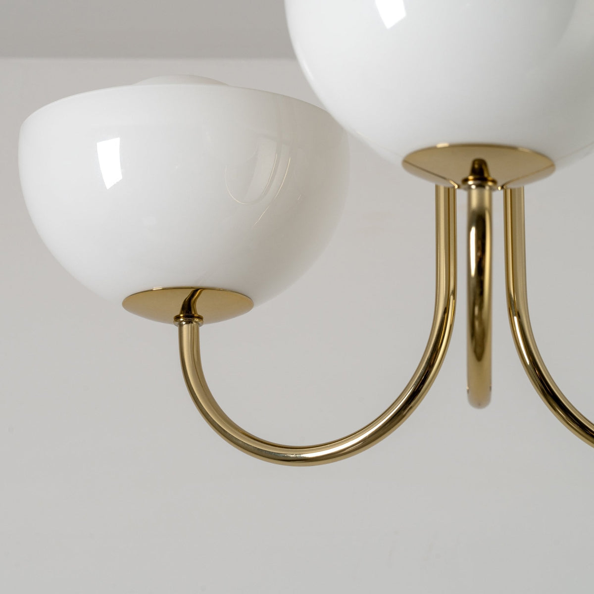 A close up of the chandelier's curved arms and opal glass shades.