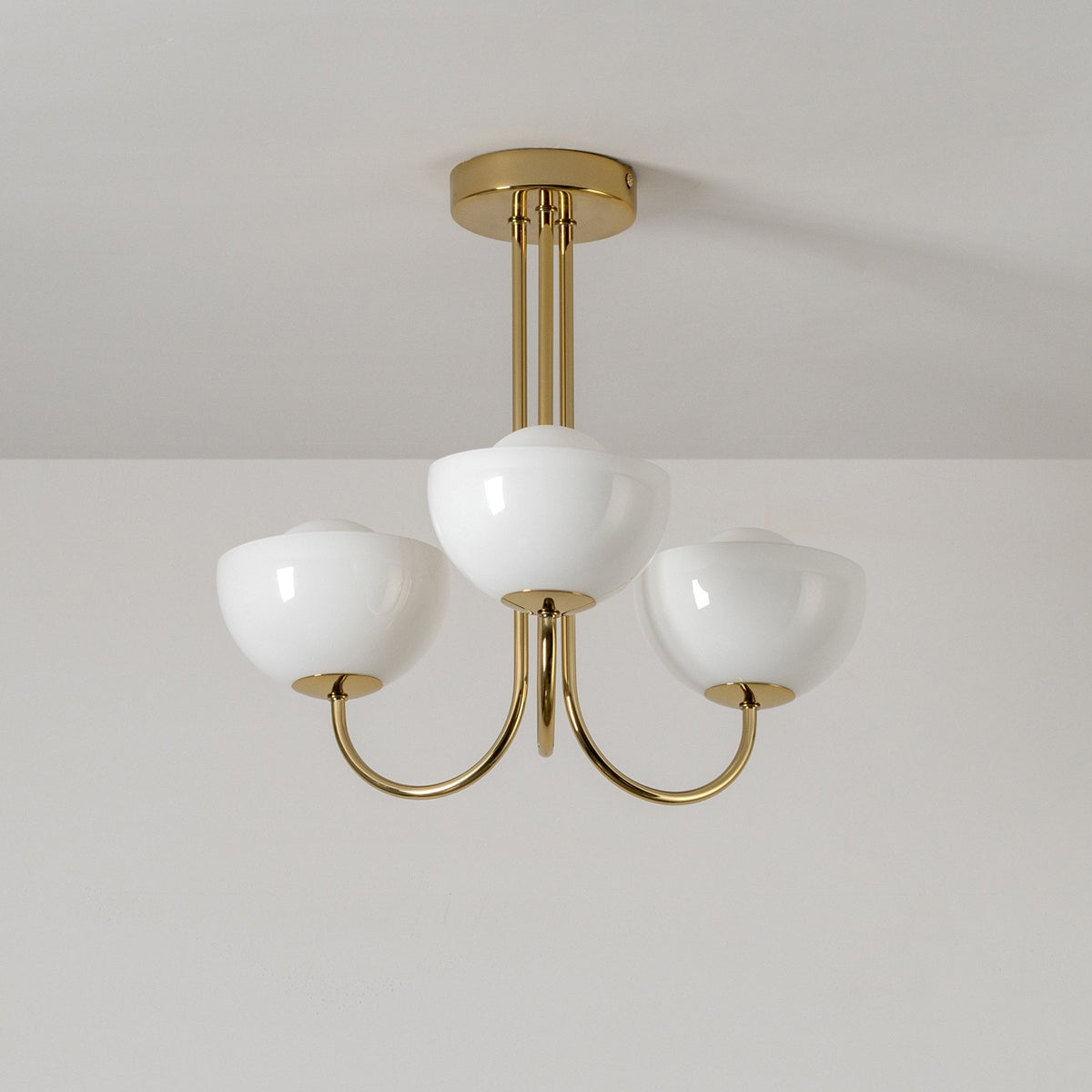 A close up of the unlit three-arm chandelier on a white ceiling.