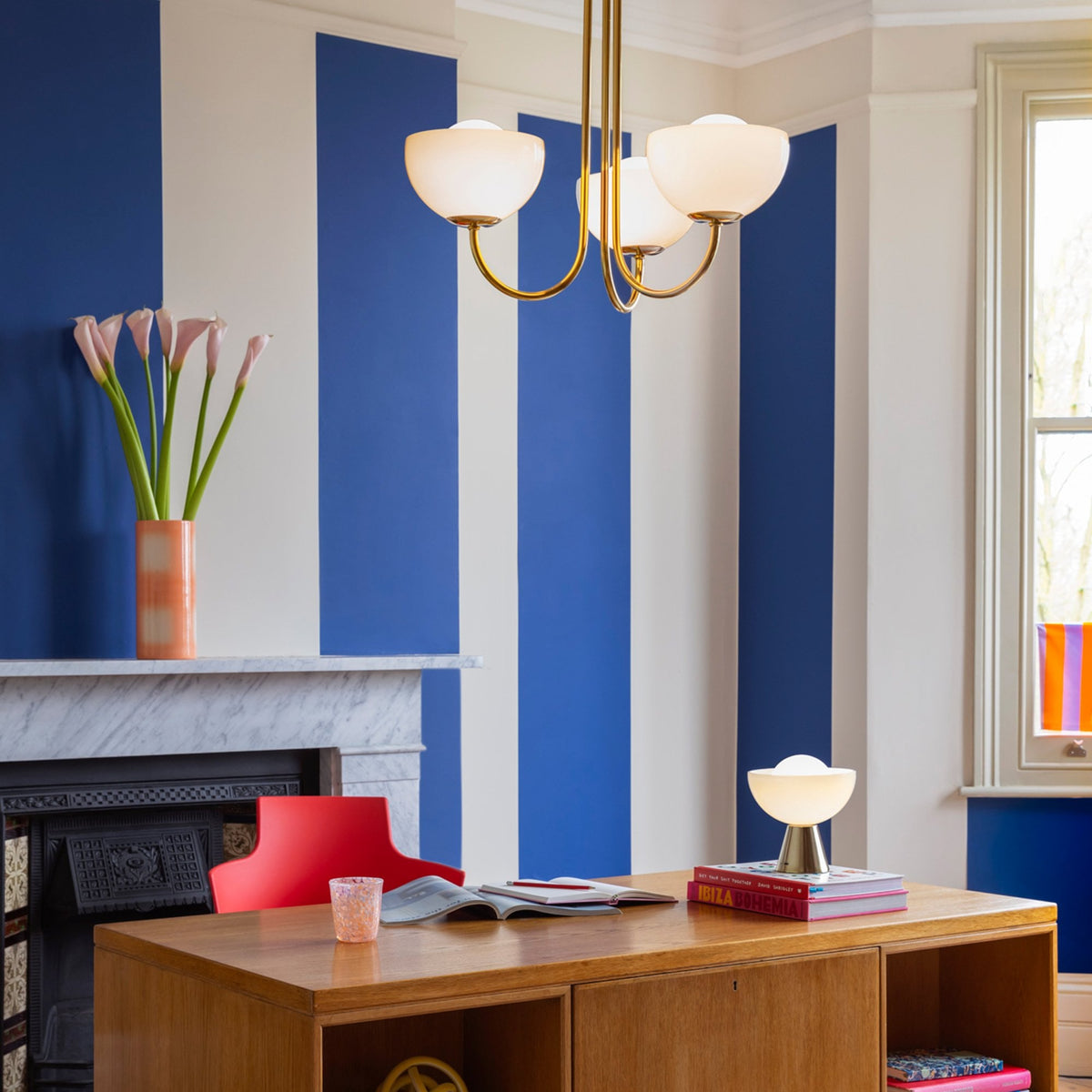 A three-arm chandelier hangs in an office with blue and white striped walls.