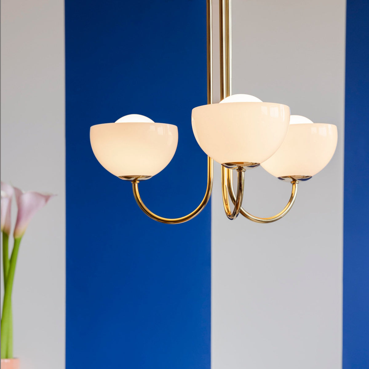 A three-arm chandelier hangs in an office with blue and white striped walls.