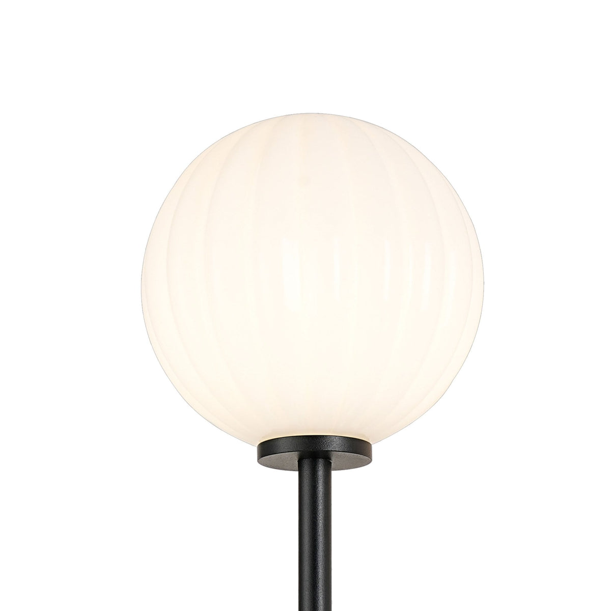 Close-up of a single ribbed white globe shade from the wall light.