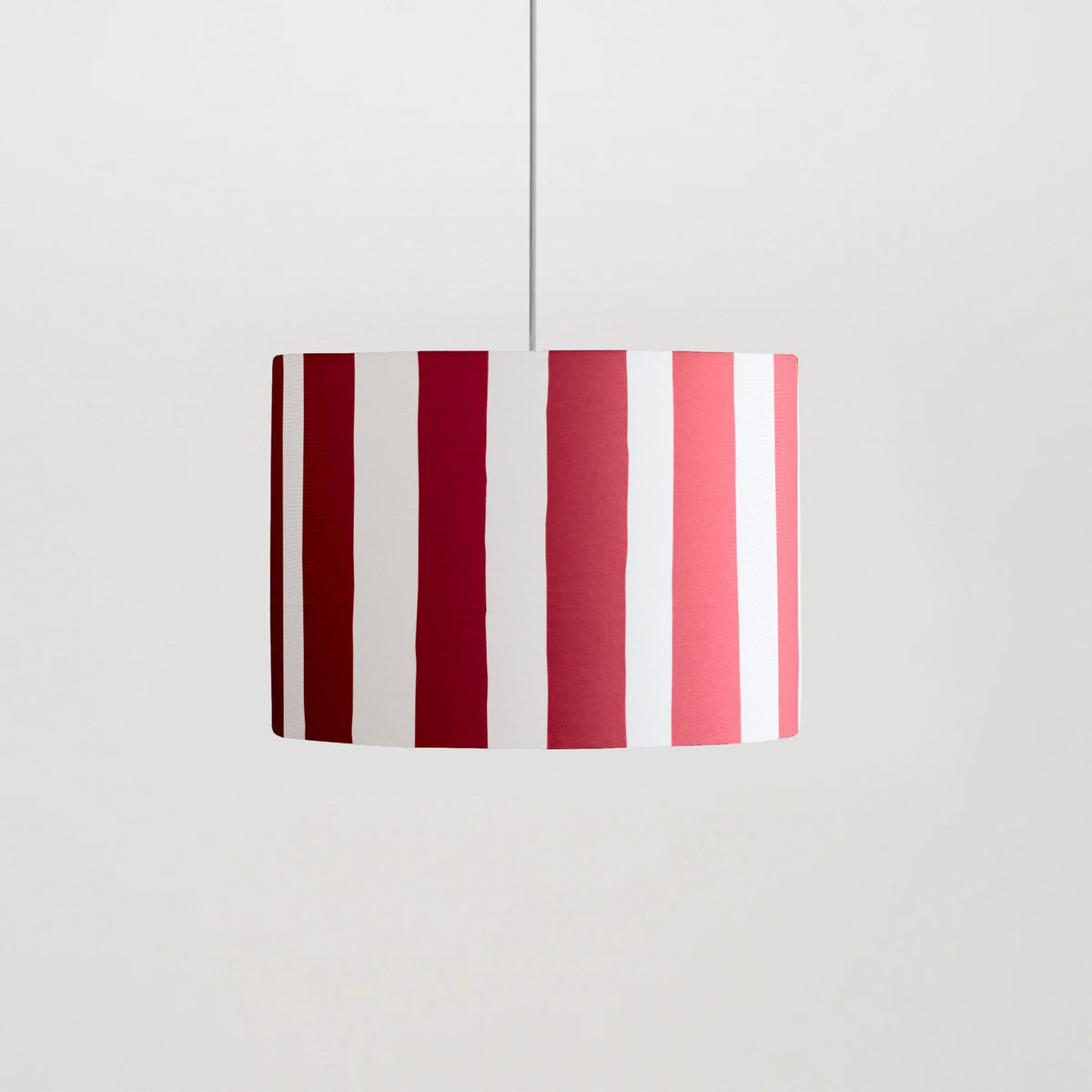 A drum lampshade with alternating vertical stripes of white and various shades of red.