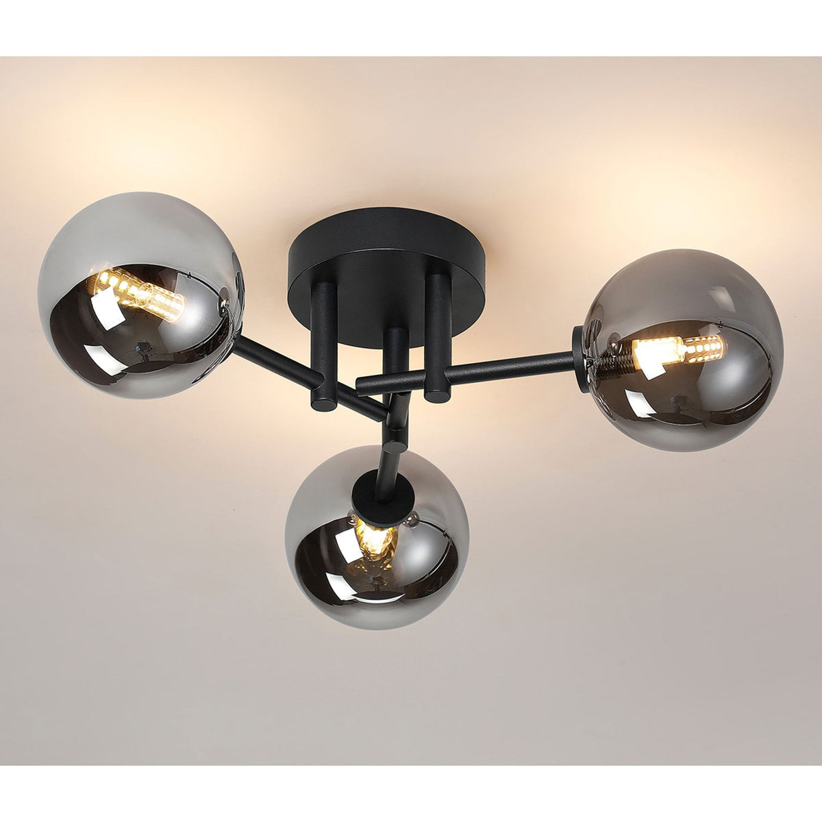 A modern three-sphere ceiling light with smoked glass shades and a black frame, illuminated.