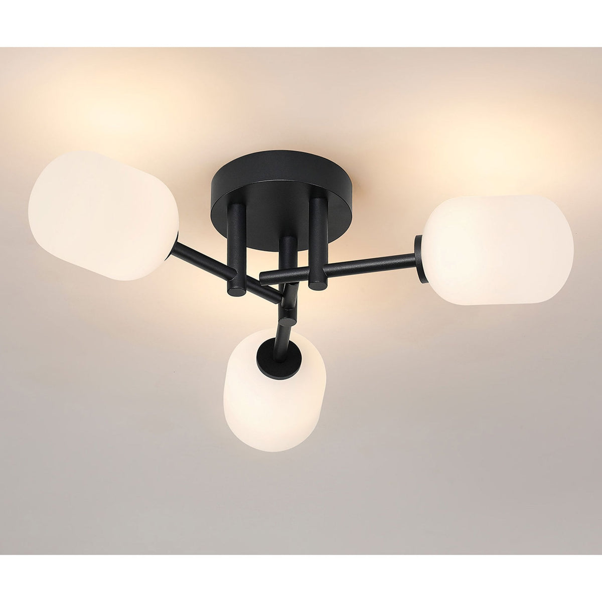 A black ceiling light with three white oval shades, emitting a warm glow.