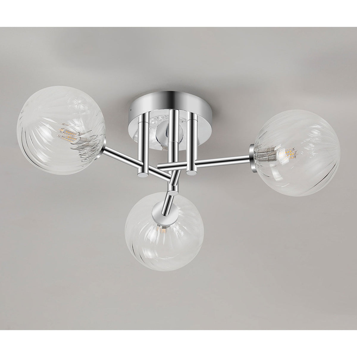 A contemporary chrome ceiling light with three clear glass orb shades against a grey ceiling.