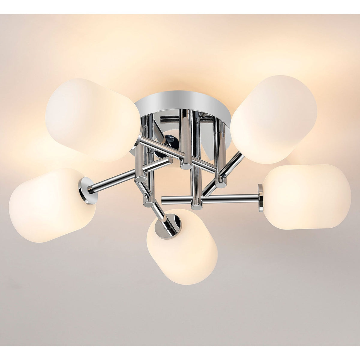 A close up of the chrome and white glass light fixture on a white ceiling, illuminated.