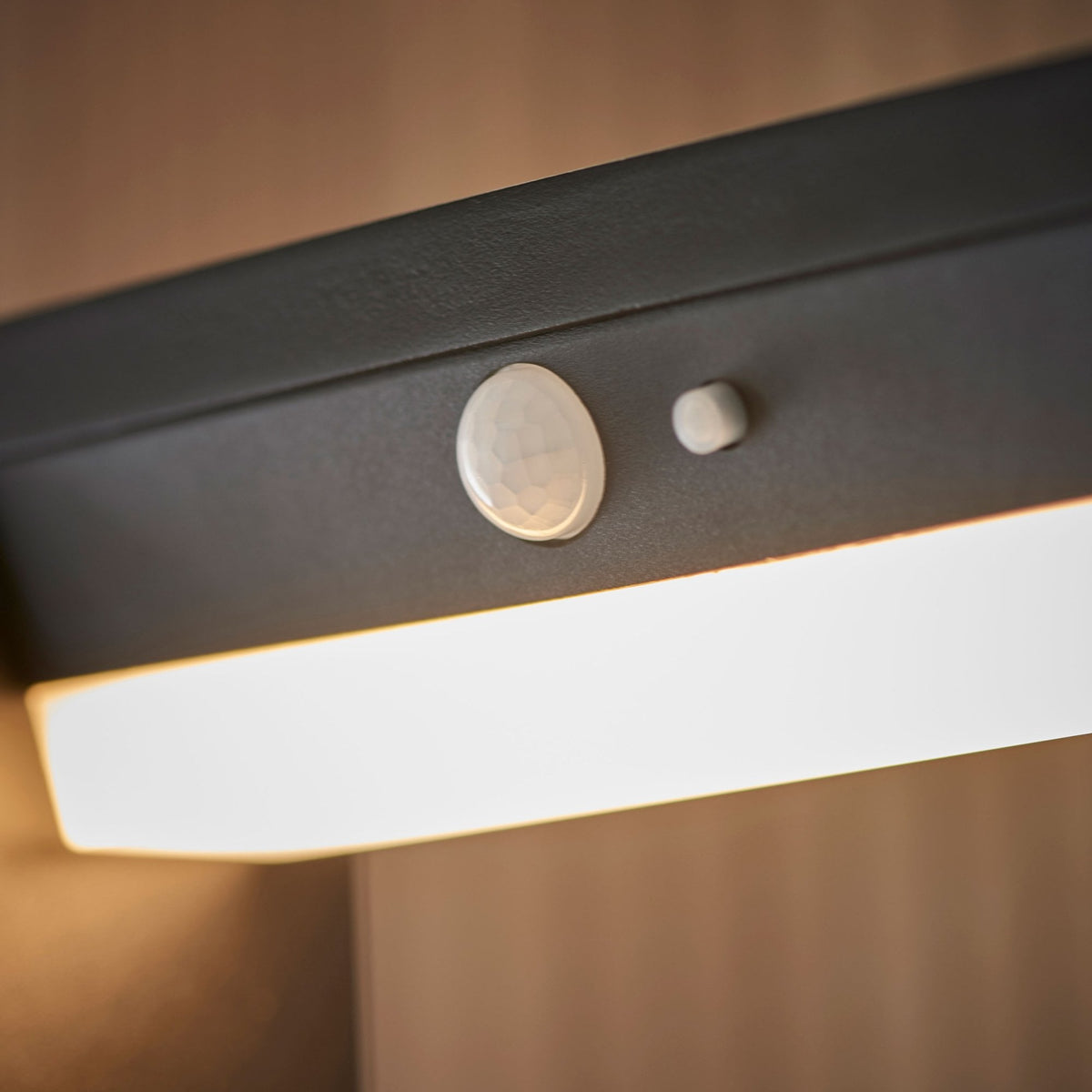 Detailed view of the motion sensor and light strip on a black outdoor bollard light.