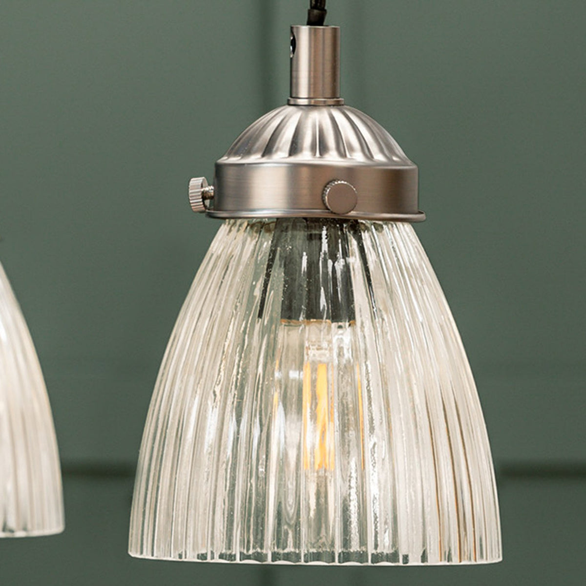 Close-up of a fluted glass pendant light with a brushed metal fitting and an exposed filament bulb.