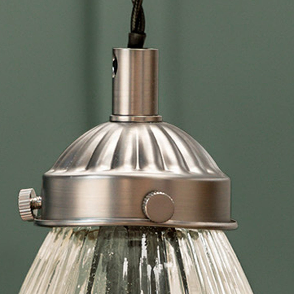 Close-up of a brushed metal light fixture with a ribbed dome and clear fluted glass shade.