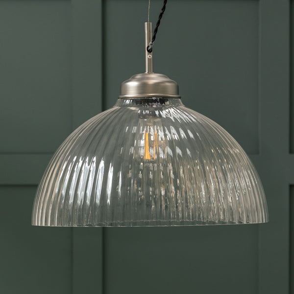 Ribbed glass dome pendant light with a brushed metal top and exposed filament bulb.