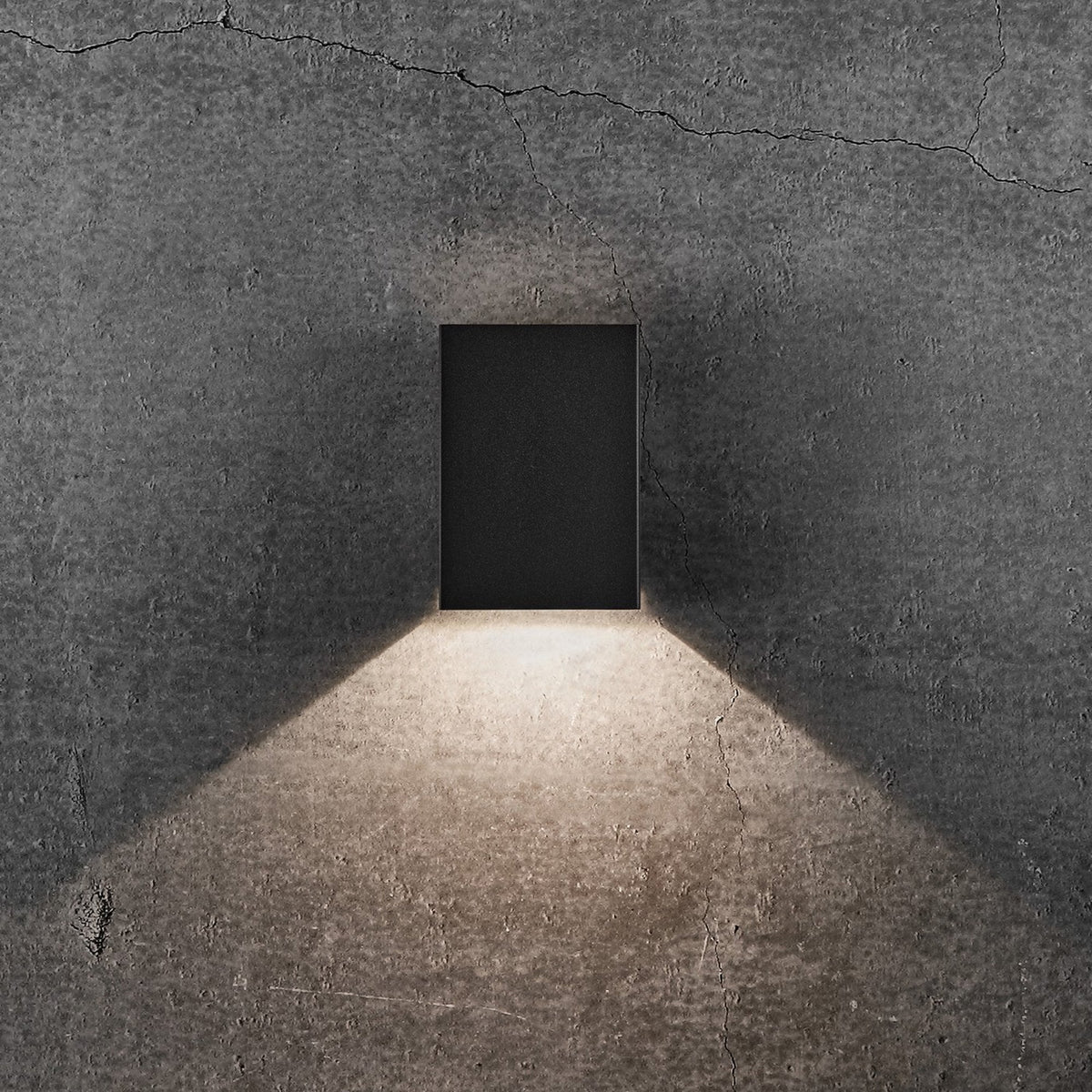 Black rectangular wall light with light shining downwards in a wide beam