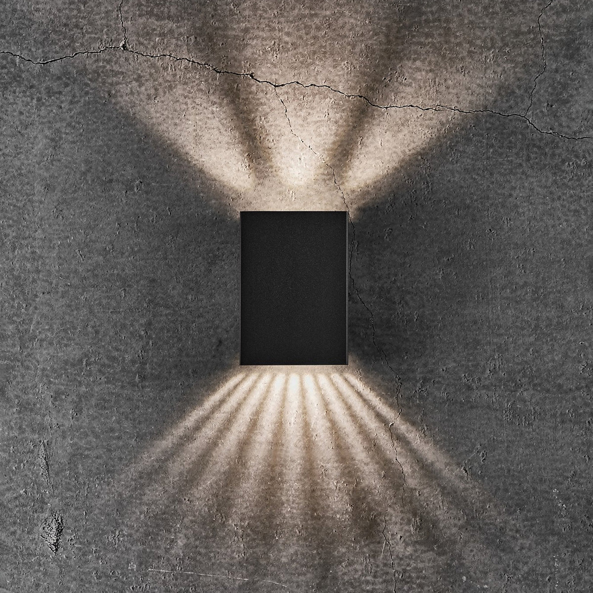 Black rectangular wall light with light shining upwards and downwards in a narrow, fanned beam
