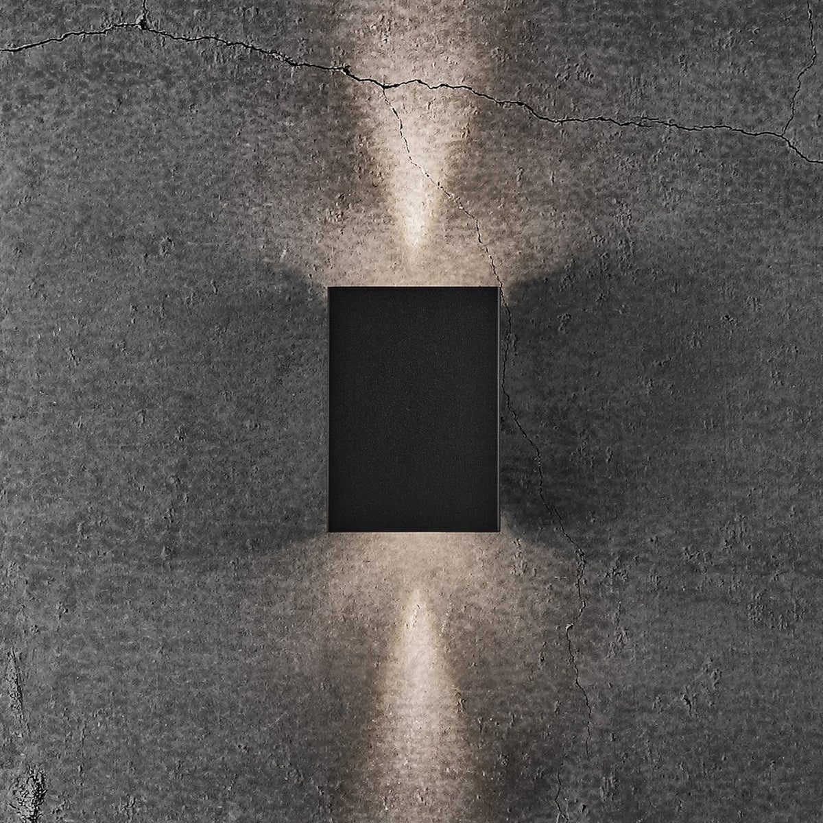 Black rectangular wall light with light shining upwards and downwards in a narrow beam