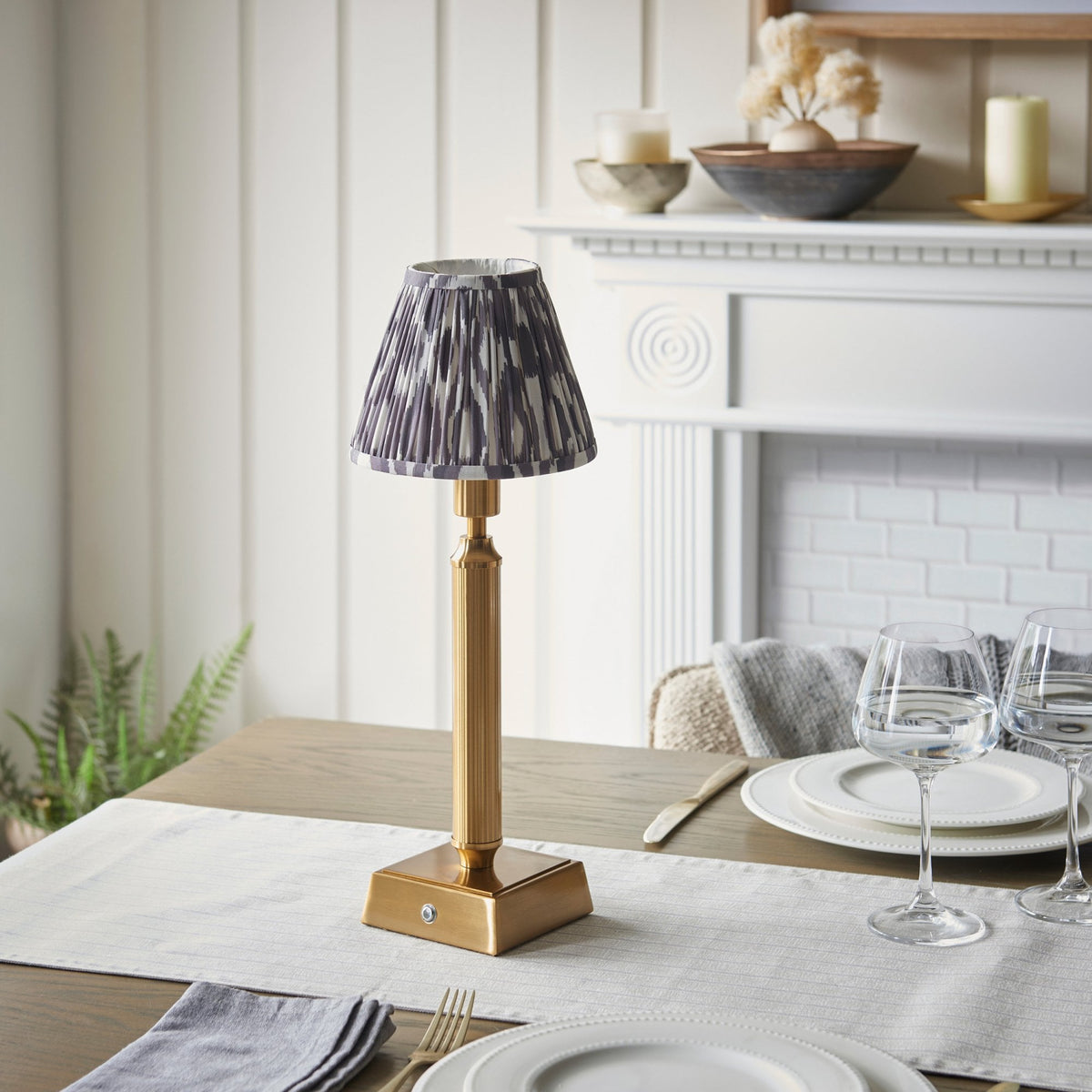 A rechargeable table lamp with a patterned ikat shade on a set dining table.
