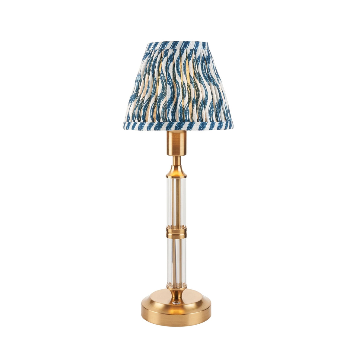 A small table lamp with a clear and brass base and a blue patterned shade on white.