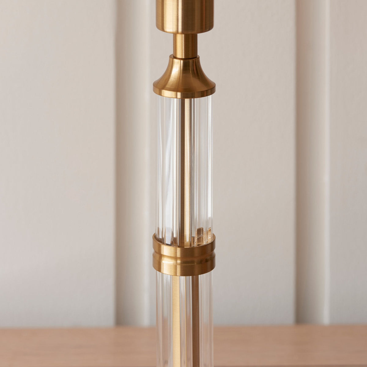 Close-up of the clear glass and brass stem of a table lamp base.