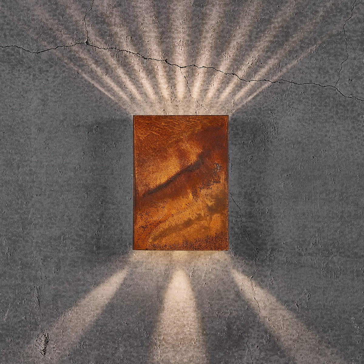 An upward and downward glowing outdoor wall light in a rustic rusted finish with an added light pattern.