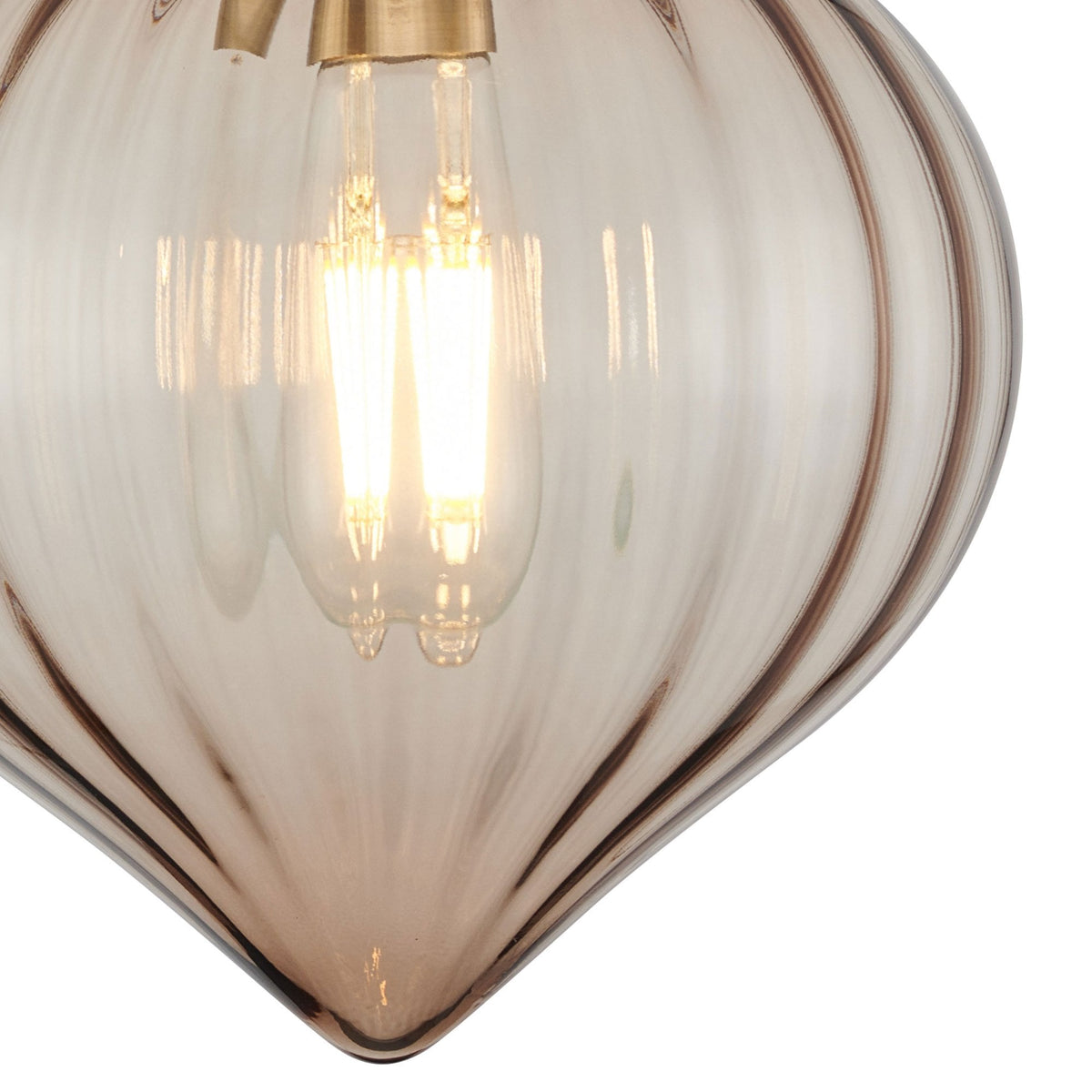 Close-up of the lit filament bulb within the clear, fluted glass shade of a wall light.
