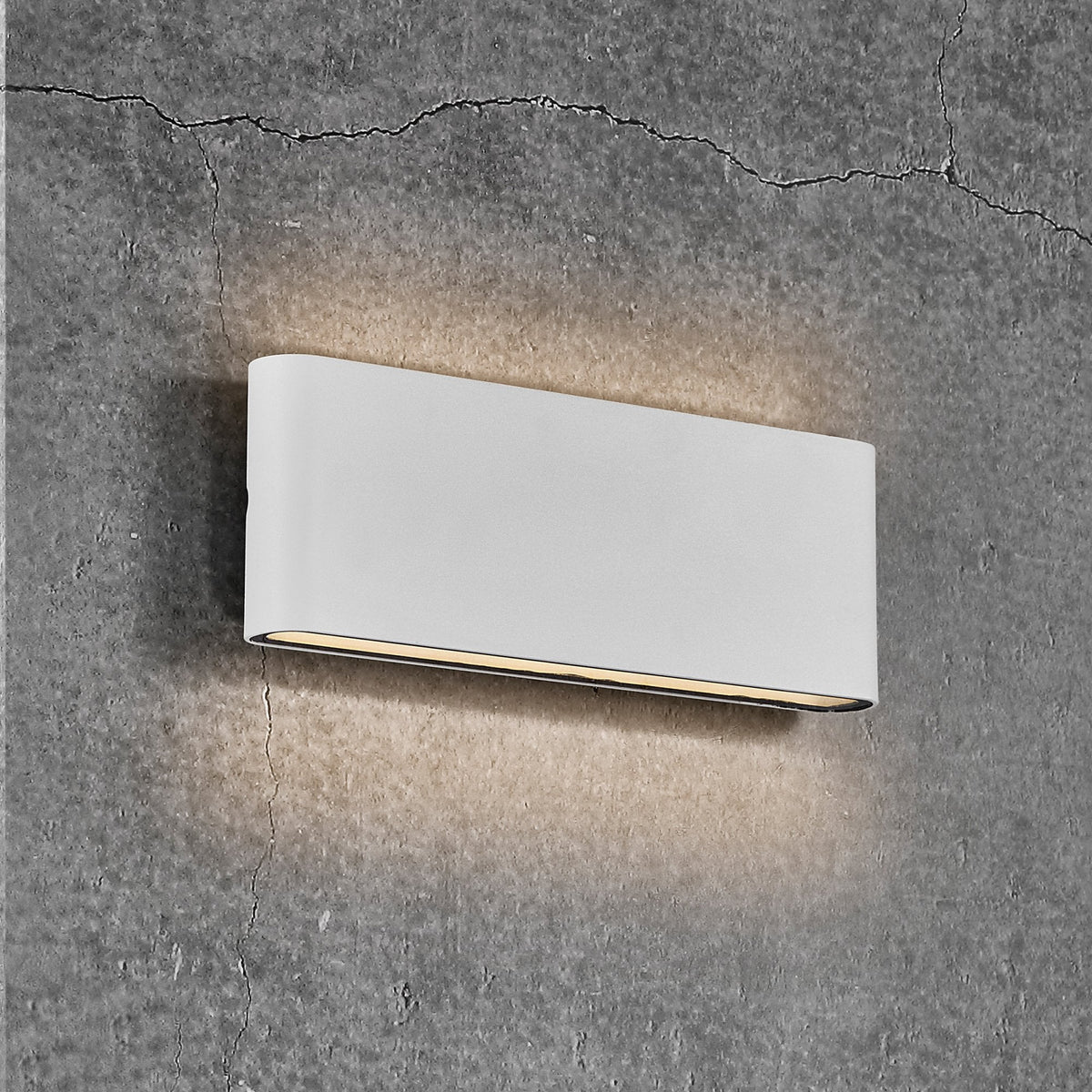A white rectangular wall light illuminates a textured grey wall.