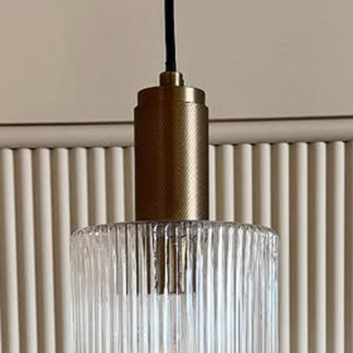 A close-up of a pendant light with a ribbed glass shade and a brass fixture.