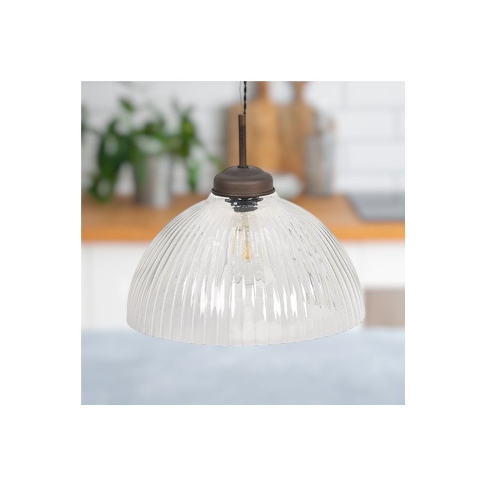 Ribbed glass pendant light with a bronze fixture and exposed bulb, hanging in a kitchen setting.