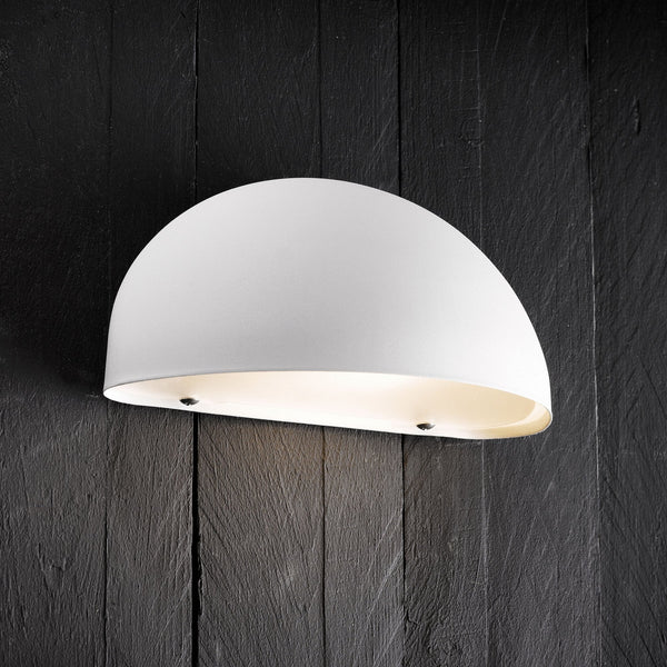 A close-up of a white, half-dome shaped outdoor wall light illuminating a dark wooden wall.