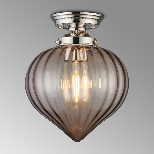 A close-up of a ceiling light featuring a polished nickel base and a smoked fluted glass shade.