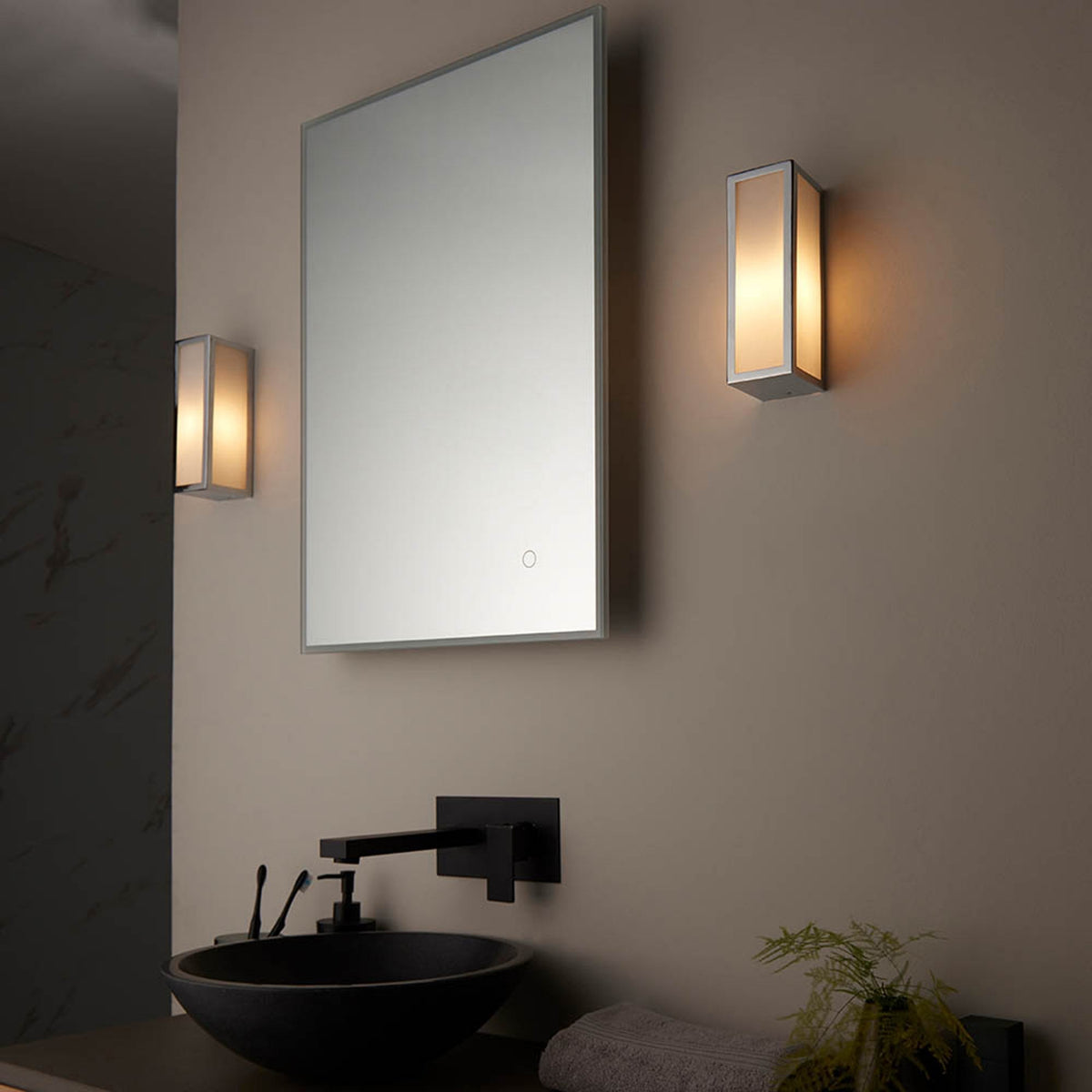 Two rectangular wall lights flank a mirror above a black sink and faucet in a modern bathroom.