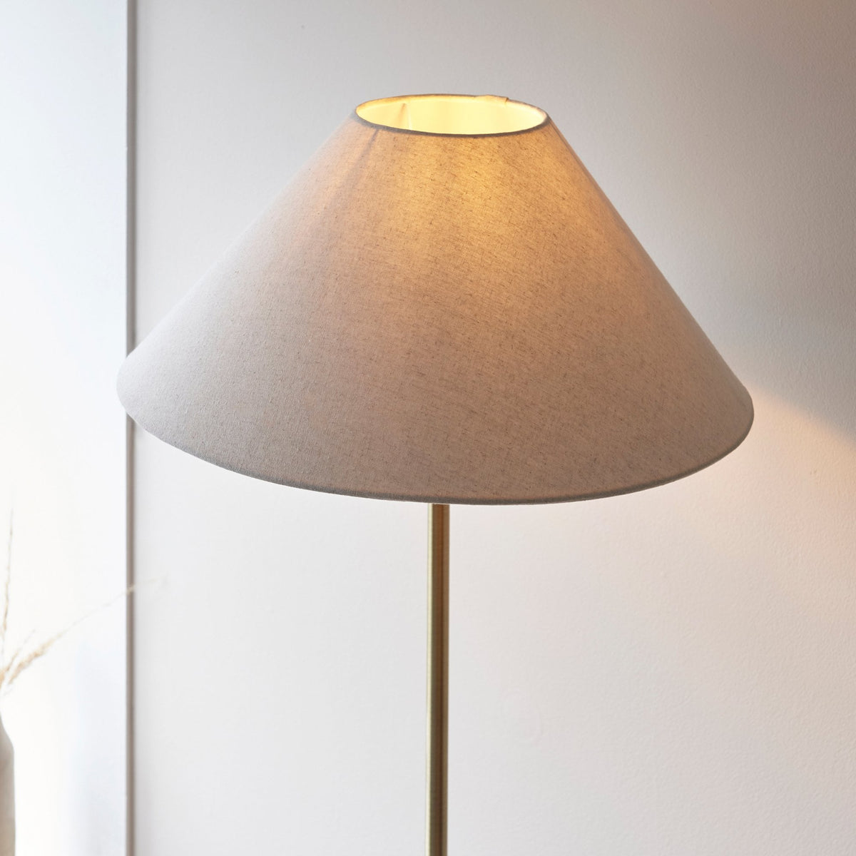 Close-up of a cream-colored, conical lamp shade casting a warm glow.