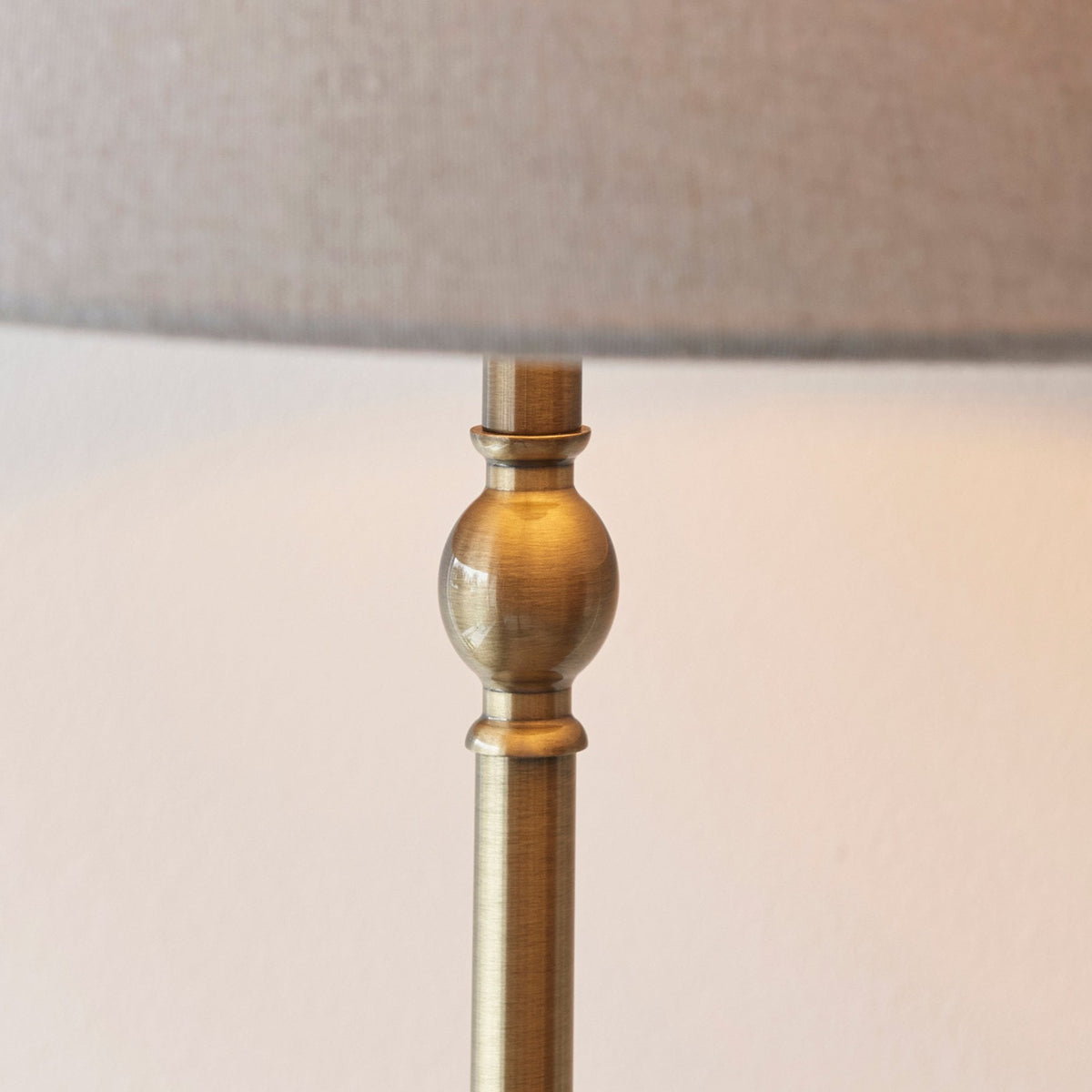Detailed view of the decorative brass finial on the stem of a floor lamp.