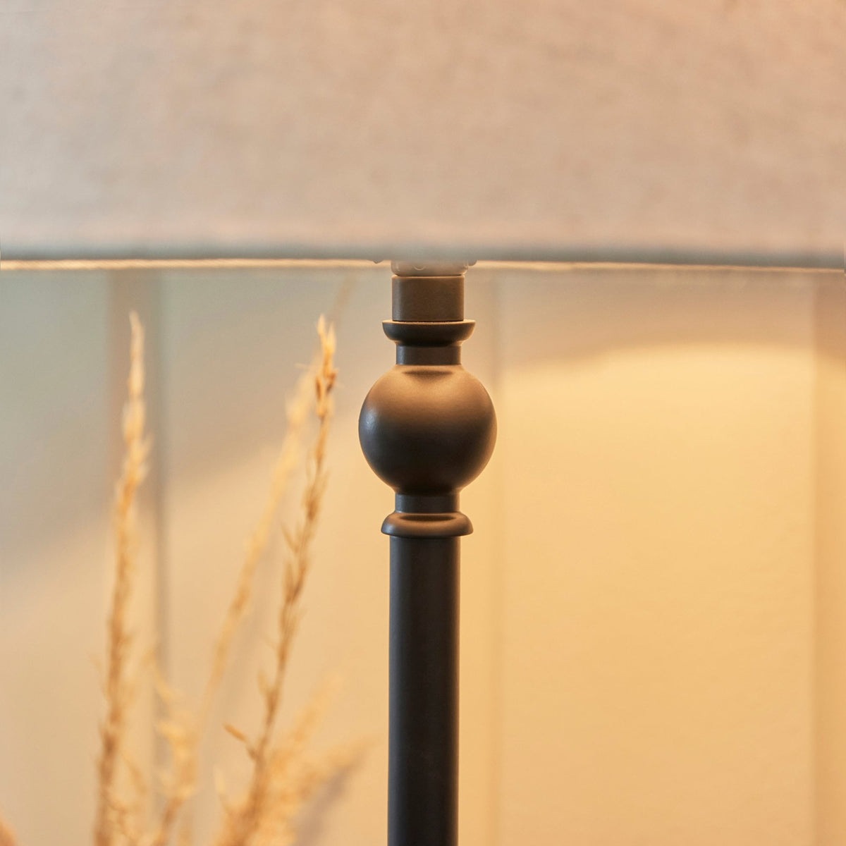 A close-up shot of the antique black table lamp's metal base with a grey lampshade.