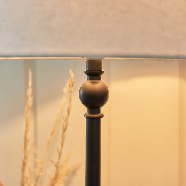 A close-up shot of the antique black table lamp's metal base with a grey lampshade.