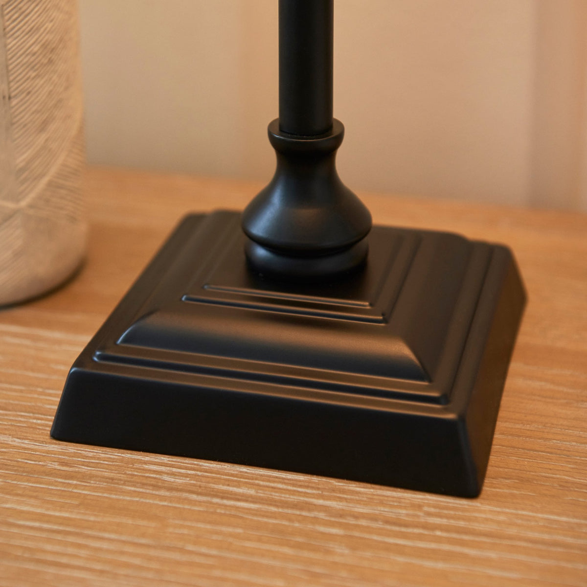 A close-up shot of the antique black table lamp's square, tiered metal base.