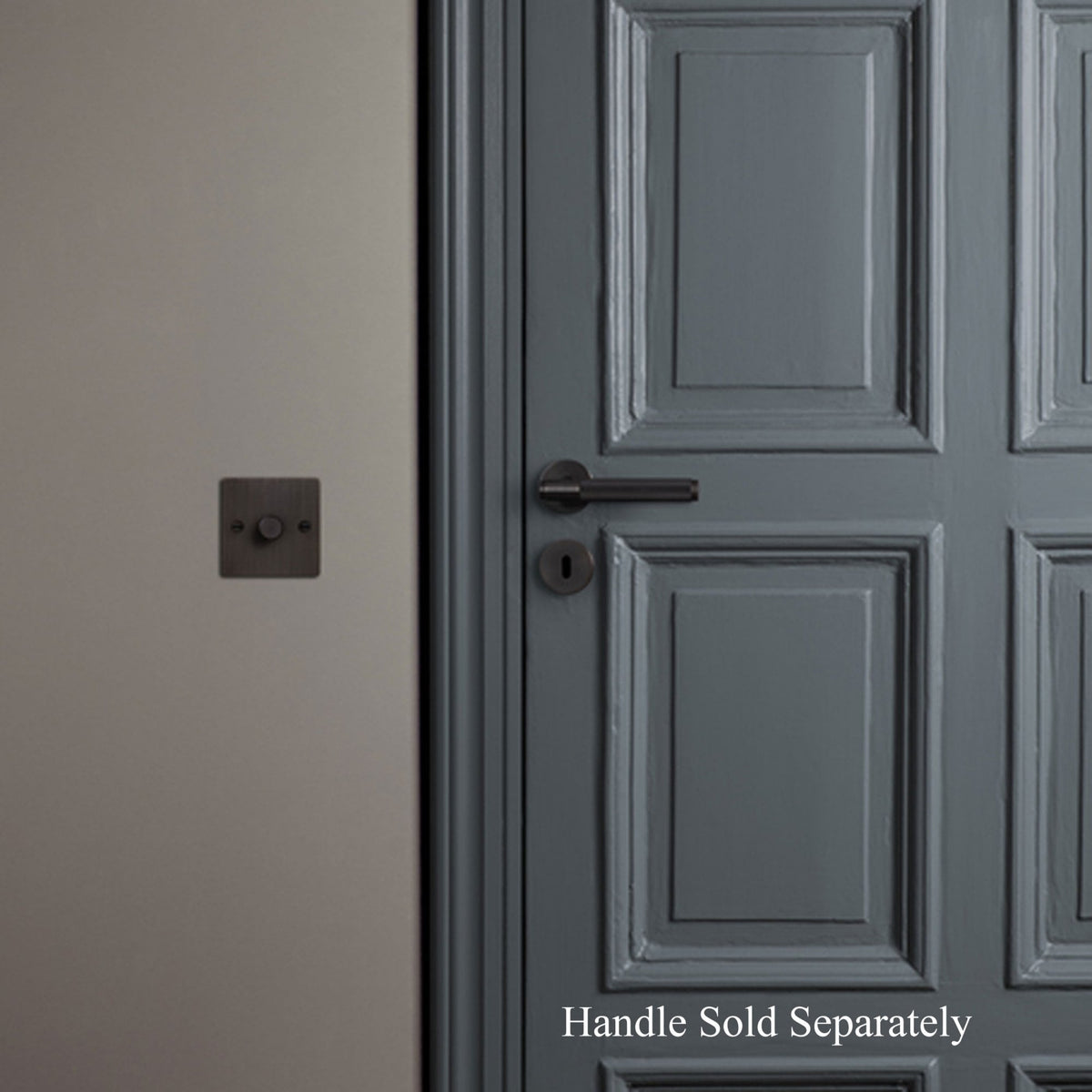 A black keyhole escutcheon on a grey door with a light switch on the wall.