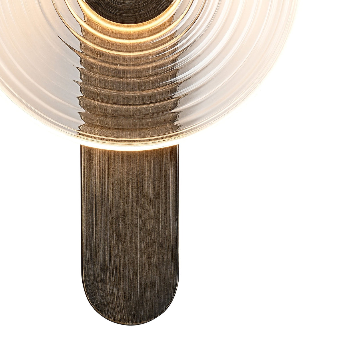 Close-up of a modern wall lamp's clear, ribbed glass shade and dark metal base.