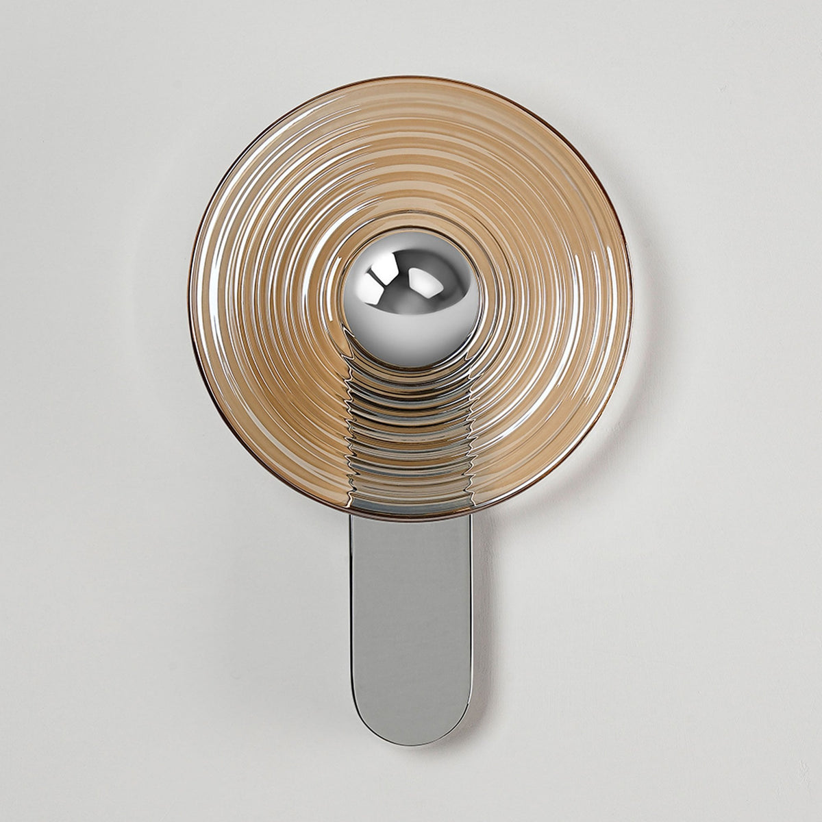 A modern wall lamp featuring a round amber-tinted glass shade and a polished silver base.