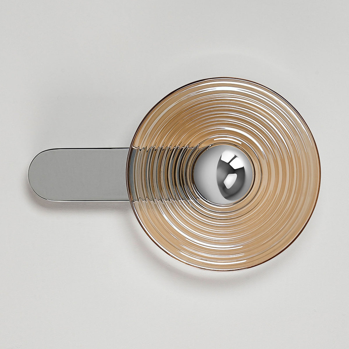 A contemporary wall lamp with a round amber glass shade and a polished silver horizontal base.