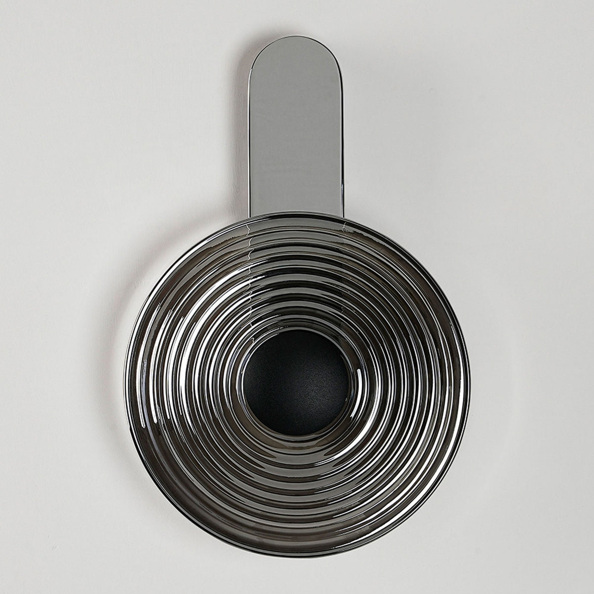 A modern chrome wall light with a circular, ridged shade, fixed vertically to a wall.