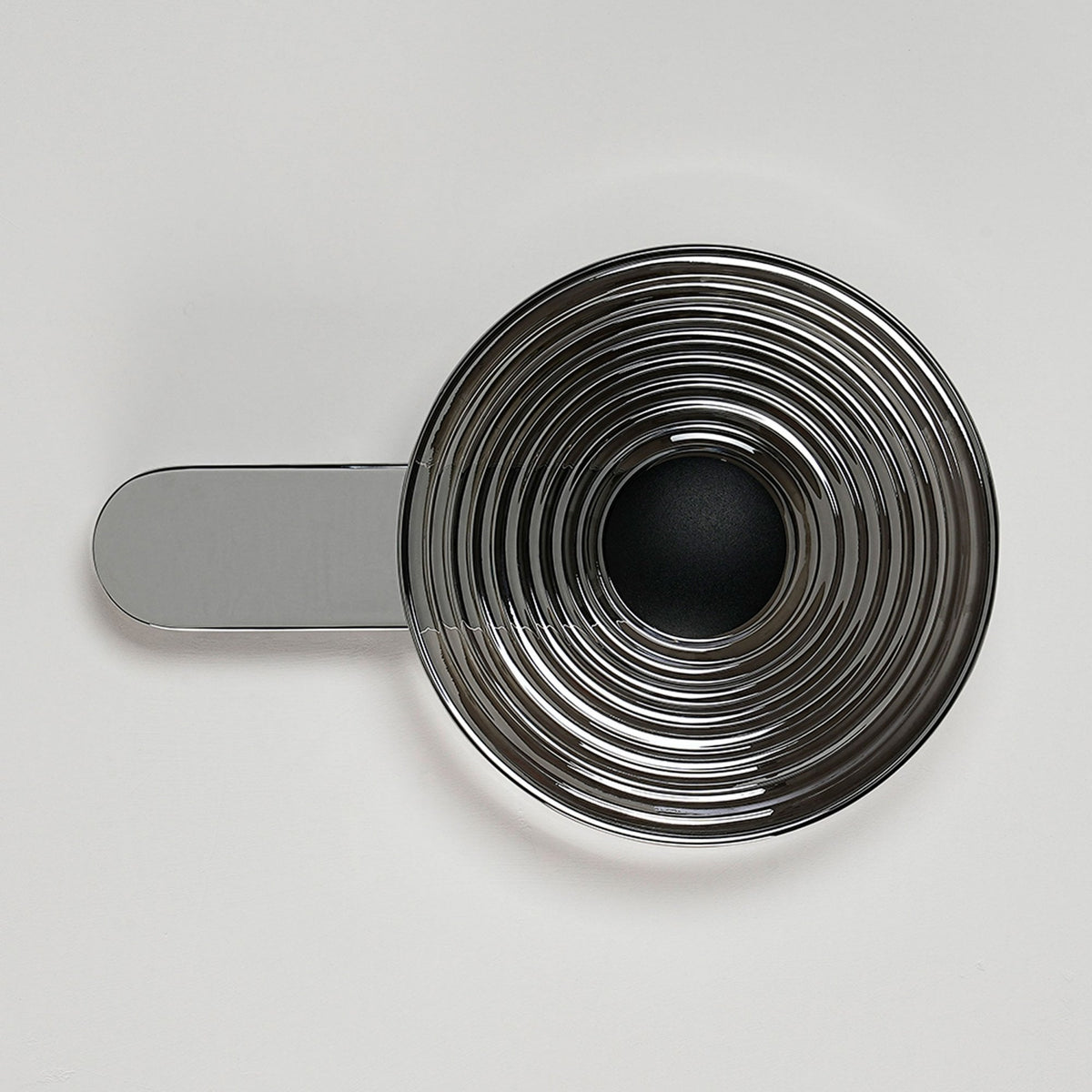 A modern chrome wall light with a circular, ridged shade, fixed horizontally to a wall.