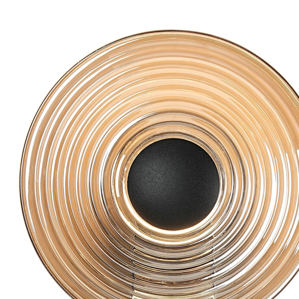 A close-up of the ridged, circular shade of the illuminated chrome wall light.