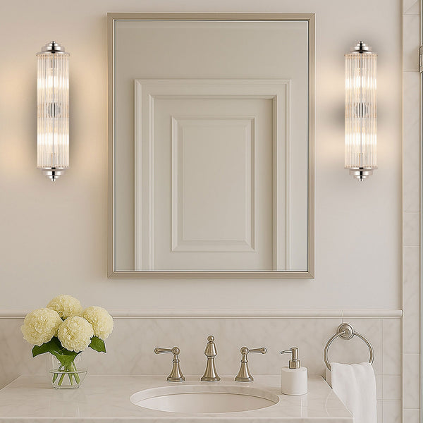 Two polished nickel wall lights illuminating a bathroom vanity mirror and sink.