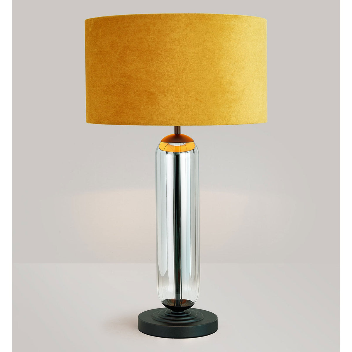 A modern chrome table lamp with a dark yellow velvet shade on a light background.