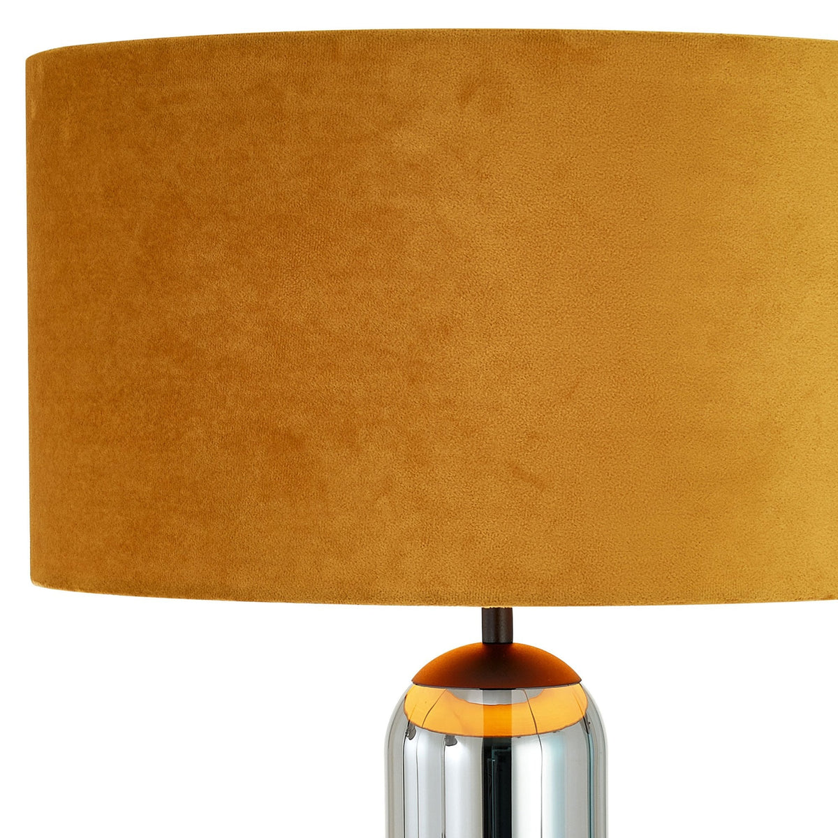Close-up of the dark yellow velvet cylindrical shade of a modern table lamp.