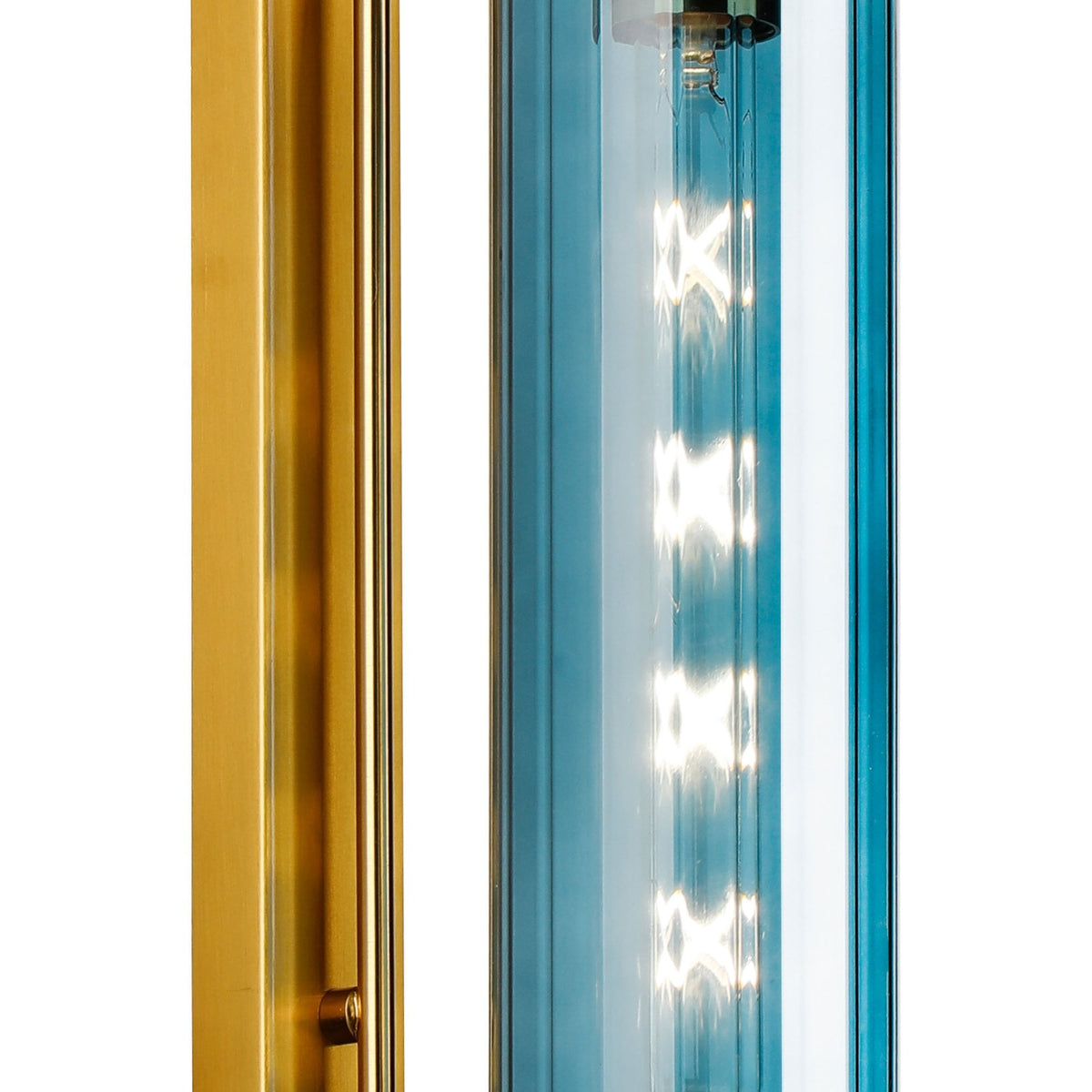 Close-up of the illuminated blue glass cylinder and brass fixture of a modern wall light.