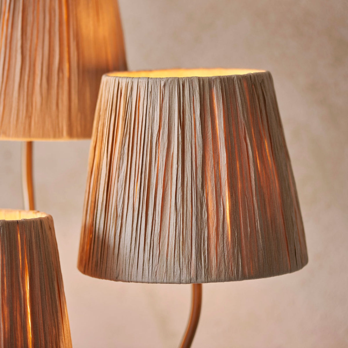 Close-up of a single pleated raffia lamp shade, glowing warmly.