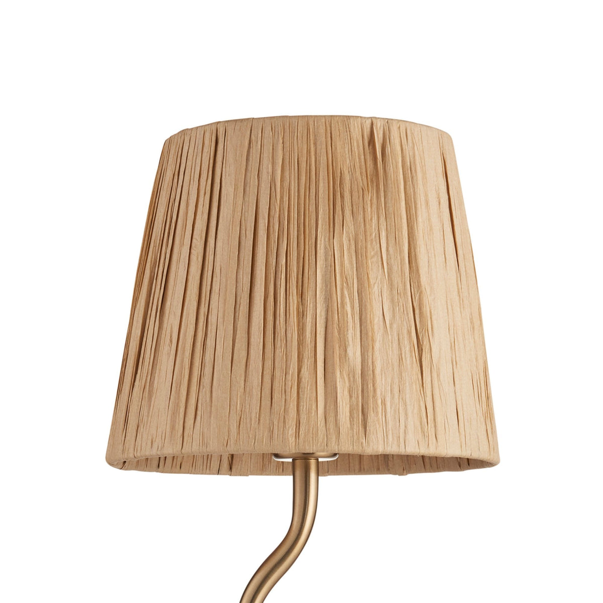 Close-up of the pleated beige shade of a table lamp with a gold wavy stem.