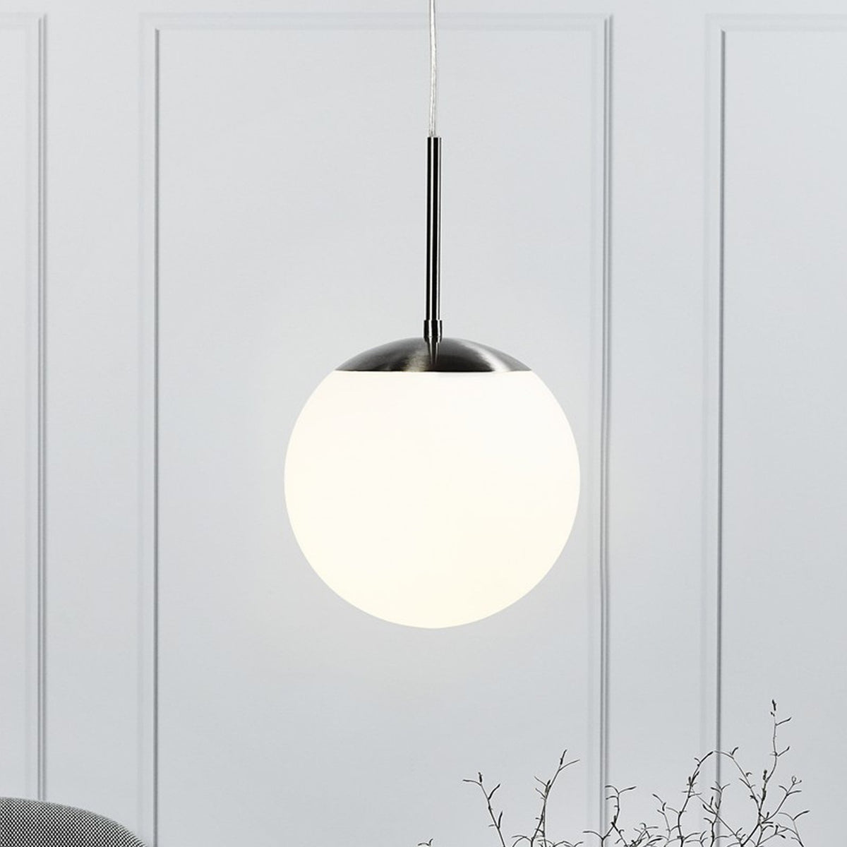 A close-up of a pendant light with a spherical white shade and brushed steel fitting.